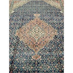 Persian pale indigo and peach ground rug, shaped central medallion within a field of repeating Herati motifs, the guarded border decorated with repeating stylised plant motifs