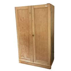 Victorian stripped pine press wardrobe, fitted with two panelled doors enclosing three sliding trays over two drawers, and sliding hanging rail with coat hooks over a fall-front cupboard, skirted base