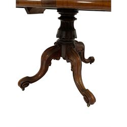 Victorian rosewood loo table, the oval top over one carved and turned column, leading into four scrolled supports, terminating in brass castors 
