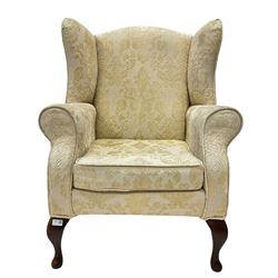 20th century wingback armchair, upholstered in ivory floral damask, raised on cabriole front supports 