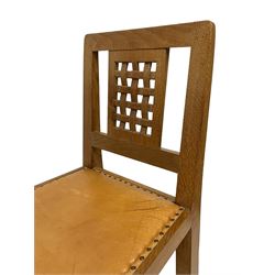 Mouseman - pair of oak dining or side chairs, pierced and carved lattice back over tan leather upholstered seat with stud band, on octagonal front supports joined by plain H-stretchers, by the workshop of Robert Thompson, Kilburn