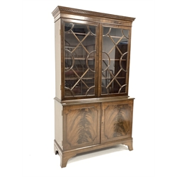 20th century Georgian design mahogany bookcase on cupboard, dentil cornice over double astragal glazed doors enclosing three shelves, two fielded doors under, raised on shaped bracket supports 