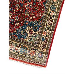 Persian Mahallat crimson ground rug, the densely decorated floral field with a central pole medallion, the curled indigo spandrels with palmette motifs, enclosed by an ivory border decorated with repeating foliate designs and stylised plant motifs