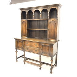 18th century style oak dresser, two open shelves over two arched panelled cupboards, fitted cutlery drawer and another drawer to base, flanked by two further cupboards, raised on turned and block supports, W153cm, H201cm, D56cm