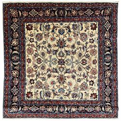 Persian ivory ground square rug, central floral pole medallion with surrounding palmettes connected by scrolling branches, the indigo border with crimson guards decorated with  stylised foliate motifs and leafage