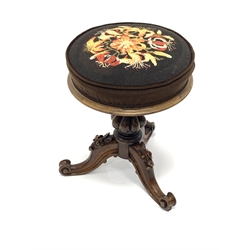 Early Victorian rosewood revolving adjustable piano stool, cushioned seat upholstered in floral needlework cover, lobe carbed baluster column support, three out splayed flower head and foliage carved supports with scroll carved terminals, D38cm