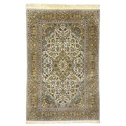 Pair Persian Kashan ivory ground rugs, all-over scrolled and interlacing foliate design with stylised plant motifs, central floral medallion and matching spandrels, the guarded border decorated with trailing foliage design