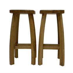 Pair Arts & Crafts design light oak bar stools, square saddle shaped seat, raised on square bow supports united by stretchers