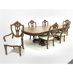 Mid to late 20th century American walnut dining table, the cross banded and quarter sawn veneered top with leaf carved frieze raised on two baluster turned and leaf carved pedestals with trefoil platform bases and reeded and scrolled feet, (200cm/290cm x 118cm, H77cm) together with a set of six (4+2) matching walnut dining chairs, with shield backs, damask covered seat pads and turned and reeded front support (W65cm)