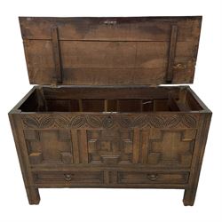 18th century oak mule chest, rectangular hinged top enclosing candle box, the frieze carved with foliate lunettes over three geometric panels with heavy moulded edges, inscribed 'EM' in studwork, fitted with two drawers to base, on stile supports