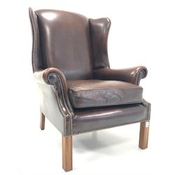 George III style wing back armchair, upholstered in studded brown leather, raised on square moulded front supports W79cm