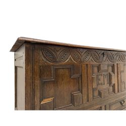 18th century oak mule chest, rectangular hinged top enclosing candle box, the frieze carved with foliate lunettes over three geometric panels with heavy moulded edges, inscribed 'EM' in studwork, fitted with two drawers to base, on stile supports