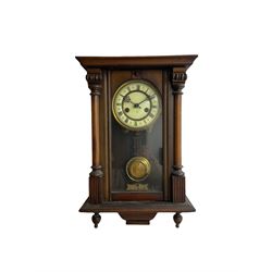 A German eight-day spring driven wall clock with a HAC movement sounding the hours and half hours on a coiled gong, rectangular case with a fully glazed door flanked by turned pillars, with glazed side panels and two pendant finials, two-part ivorine dial with Roman numerals and gothic steel hands, gridiron pendulum and beat plate. With key.  



