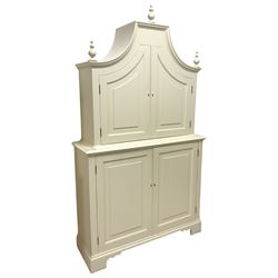 Cream painted cupboard, the upper section with moulded pagoda top with three turned finials, enclosed by two panelled doors, the lower section with moulded rectangular top over two panelled doors, fitted with adjustable shelves, on bracket feet
Provenance: From the Estate of the late Dowager Lady St Oswald