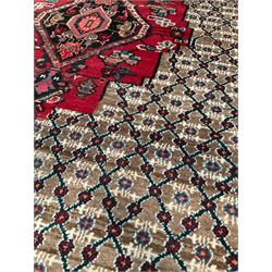Persian rug with one central red medallion on beige field with geometric borders