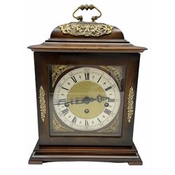 A 20th century three train mantle clock in the style of an 18th century bracket clock, case with an inverted bell top and basket top handle, square brass dial with a slivered chapter ring, roman numerals and five-minute Arabic’s, decorative steel hands with a matted dial center and cherub spandrels, striking the hours and quarters on five gong rods.