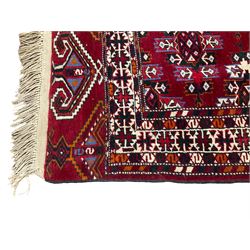 Anatolian crimson ground rug, field decorated with all-over uniform geometric Gul motifs, the multi-band border with repeating hexagonal designs, with repeating Elibelinde motifs