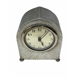An eight-day English Art Nouveau “Liberty” style spring driven mantle clock by T.W. Ward in a hammered pewter case on four bun feet, with a chrome bezel and 3” silvered dial, Arabic numerals and minute track, with integral key, hand set and wound from the rear.