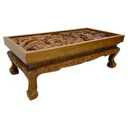 Carved hardwood coffee table, the rectangular top deeply carved depicting village scene with trees and elephants, shaped frieze rails carved with flower heads and foliage
