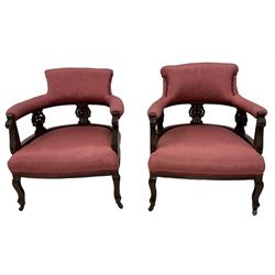 Pair late Victorian mahogany framed tub armchairs, scrolled back over pierced and carved foliate splats, sprung seat upholstered pink fabric, on cabriole supports with castors