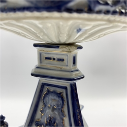 Pair of 19th century German blue and white porcelain 'oil' lamps, the reservoir relief moulded with Putti on a winged sphinx support and triform base, JR monogram to base, H29cm 