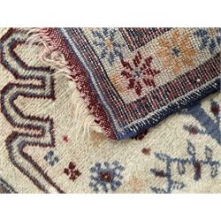 Persian Baluchi ivory ground rug, the field with a shaped crimson outline encasing a stylised urn and plant motif with geometric qualities, the triple band border with repeating star motifs in indigo and red