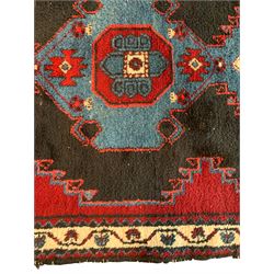 Persian Tuyserkan crimson ground rug, the central indigo geometric motif with stylised plant symbols, the spandrels as figure motifs, guarded ivory border with interconnected flower heads