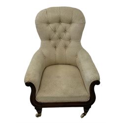 William IV rosewood framed library armchair, spoon shaped back with scrolled arms carved with rosette decoration, upholstered in buttoned cream fabric with sprung seat, raised on turned supports terminating in brass cups and ceramic castors