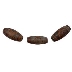 Three Tibetan Dzi stone beads each with decorative symbols approx 3cm long 