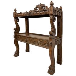 19th century carved oak buffet, raised pediment carved with scrolling foliage and two griffin heads, two tiers with foliate carved edges, the upper tier frieze carved with winged putto mask, scale carved dolphin uprights and serpentine supports carved with paw feet