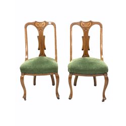 Pair of Art Nouveau period oak dining chairs, stylised floral inlay over a splat back, upholstered in overstuffed green fabric, raised on cabriole supports terminating in castors W48cm