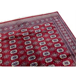 Persian Bokhara claret ground rug, the field decorated with six columns of Gul motifs, the guarded border with indigo outlines and repeating geometric motifs
