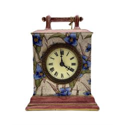 A continental porcelain table clock in the aesthetic style c1900, square case with carrying handle and decorative flowers in applied relief, with a French 30hr “tic-tack” timepiece movement and integral pendulum, 2-1/2” enamel dial with roman numerals and minute markers, steel Fleur di lis hands and 3” unglazed brass bezel. With key.


