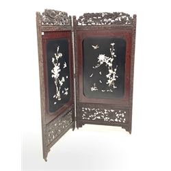 Early 20th century Japanese bi-fold privacy screen, with profusely carved hardwood frame enclosing lacquer panels decorated with flora and bird applied in mother of pearl, on metal castors,140cm x 147cm