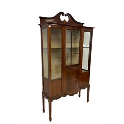 Edwardian mahogany display cabinet, moulded swans neck pediment, the frieze decorated with lozenge band, reverse bow front astragal glazed door over opposing bow front panelled cupboard inlaid with urn, two flanking glazed and panelled doors, on square tapering supports with spade feet