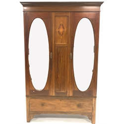 Edwardian inlaid mahogany double wardrobe, two oval mirrored doors enclosing interior fitted for hanging, one drawer under, raised on bracket supports, W125cm, H205cm, D50cm