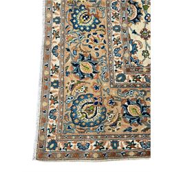 Persian Kashan rug, pale gold ground, the field decorated in blue with trailing branches and stylised plant motifs, the main border band with matched repeating design