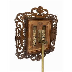 Victorian rosewood and brass music stand, floral fretwork frame enclosing needlework panel depicting music student and teacher, raised on turned upright and three splayed conforming 'C' scrolled supports 
