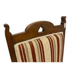Arts & Crafts period oak armchair, the cresting rail and arm splats pierced with heart motifs, upholstered in striped fabric, on turned supports