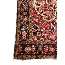 Persian ground rug, pale ground field with central medallion surrounded by trailing floral design and urns to each end, the border and spandrels decorated with flower head motifs