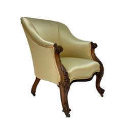 Victorian rosewood armchair, scroll carved arm terminals and floral carved uprights, upholstered in pale yellow fabric, on cabriole supports with brass castors, sprung seat