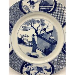 Chinese Kangxi plate decorated in blue and white with a figure looking over a wall with two figures in a garden, the border with further panels of figures, the reverse with six character mark D27cm