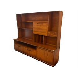 Meredew - mid-20th century teak wall unit, the raised top fitted with fall front, small drawer, shelves and record divisions, enclosed by sliding glass doors, the lower section fitted with two drawers and double cupboard