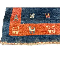 Small Persian Gabbeh indigo ground rug, comprised of three blue and red concentric squares, decorated with stylised camel motifs, retailed by Fired Earth