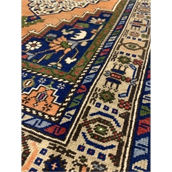 Persian ground rug, with central medallion of blues, greens, reds, and ivory, on an orange field, enclosed by multi line border