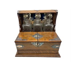 Edwardian oak three-bottle tantalus with silver-plated strapwork mounts, shield shaped plaque and swing handles, containing three later cut glass square form decanters, two hinged doors with fitted interior and secret drawer beneath, L37cm, H33cm, D29cm 