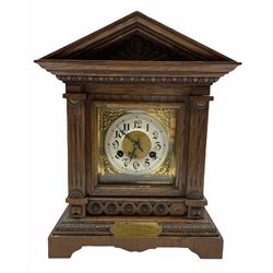 An early twentieth century German oak mantle clock in an architectural case on a shaped plinth with egg and dart moulding, the dial flanked by two reeded pillars with semi-circular carved capitals, egg and dart moulding with a deep cornice surmounted by a gabled pediment, tympanum with a shell carved motif, square brass dial with scroll spandrels and silvered chapter ring with upright Gothic Arabic numerals, steel Gothic hands, minute track and bevelled glass, eight-day going barrel movement striking the hours and half-hours on a coiled gong, rack striking recoil anchor escapement, movement stamped Junghens B07, case with a presentation plaque dated 1912.  
With pendulum.
Erhard Junghens founded the Junghans clockmaking company in Schramberg, Germany in 1861, by 1903 the company was the largest clockmaking company in the world. The company still manufactures high quality watches and clocks.
