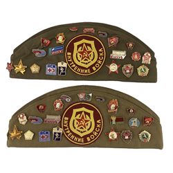 Two Russian military caps each with twenty various pins