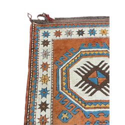 Turkish rust ground rug, two geometric medallions on plain field, the border decorated with stars within guard stripes