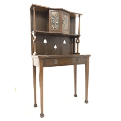 Early 20th century oak Arts and Crafts writing desk, raised back with open shelf and cupboard to centre with hammered brass panels over a fold out baize lined writing surface and single drawer, raised on square tapered supports
